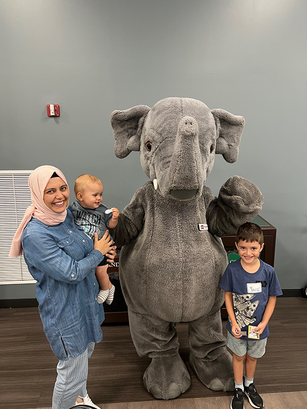 Mother with her adolescent boy and baby, posing with the Columbus Zoo's elephant mascot.