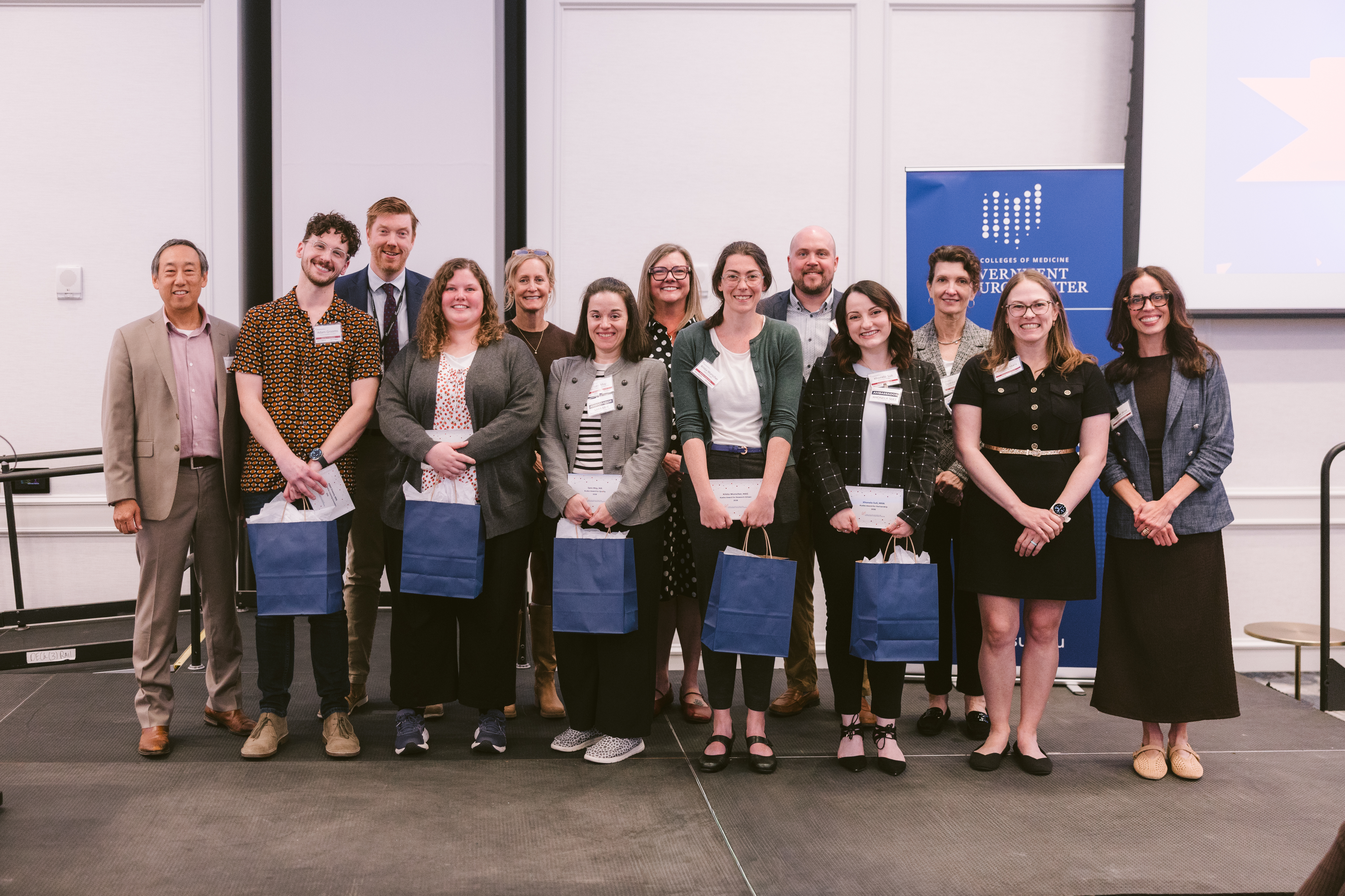 A group photo of the 6 winners of the 2026 Kudos Awards with Senior Staff on the stage at the Advance.