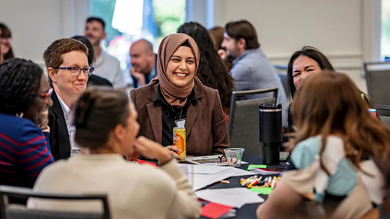 A group of women sitting around a table discussing and laughing at the GRC Staff Retreat.