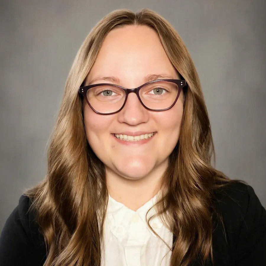 Woman with light brown hair and black glasses wearing business attire