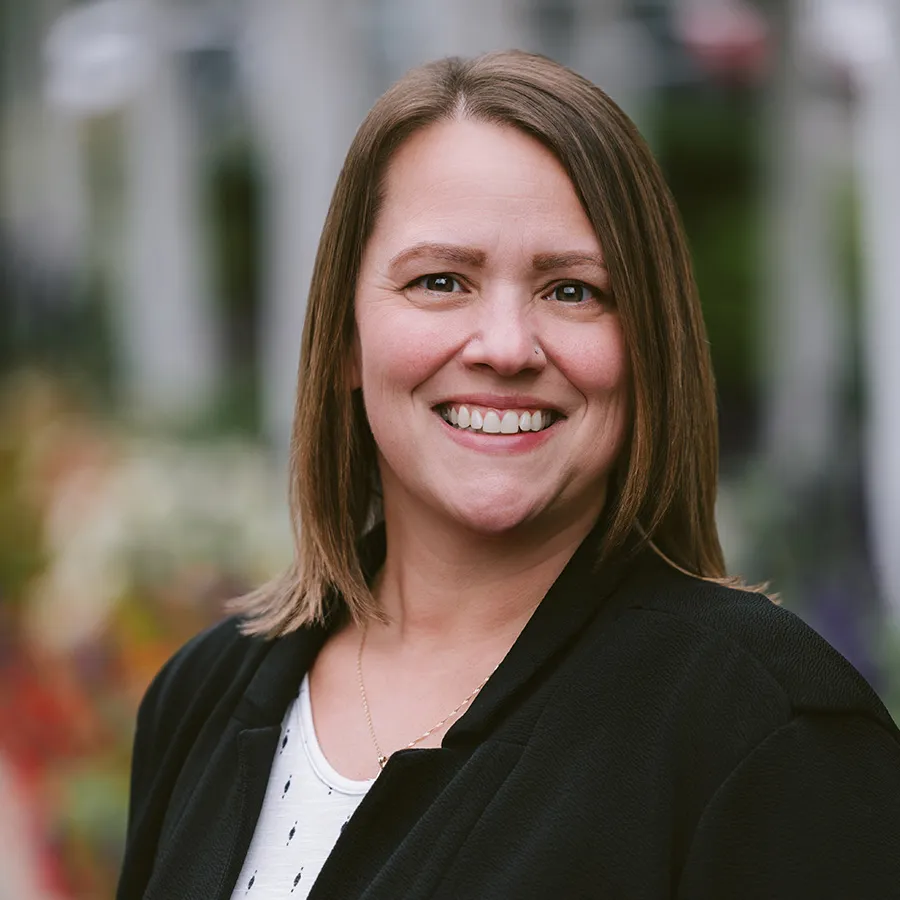 Headshot of Tia DeLong, a woman with short brown hair wearing a black blazer