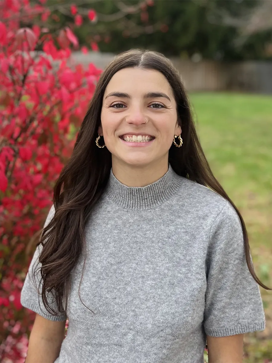 A white woman with long brown hair in a grey sweater